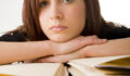 A bored looking office worker behind a large pile of files.
