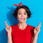 Photo of sad young brunette lady bite lip wear red t-shirt hairband isolated on blue color background.