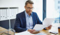 Shot of a mature businessman reading a document at his desk in an office