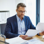 Shot of a mature businessman reading a document at his desk in an office