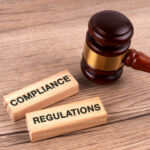 Final part of a series: Understanding the Wells process Top view of gavel and wood block with text compliance and regulations