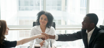 Smiling african businessman handshaking greeting caucasian businesswoman at group meeting negotiation, black satisfied entrepreneur welcoming partner shaking hand in lawyers office, respect concept