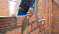 Worker building masonry house wall with bricks