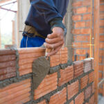 Worker building masonry house wall with bricks