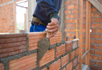 Worker building masonry house wall with bricks