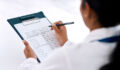 Cropped shot of an unrecognizable female doctor writing on a clipboard while working in her office