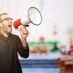 Priest religion man communicates shouting loud holding a megaphone, expressing success and positive concept, idea for marketing or sales at church