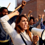 CAT concept release comments sought Young displeased woman using megaphone and shouting while protesting with group of people on city streets.