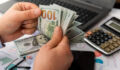 Businessman counting hundreds of dollars at his table