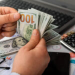 Businessman counting hundreds of dollars at his table