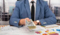 male businessman in a super suit and tie makes payments to the business at the table. Business and money concept