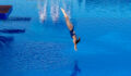 Young woman diving from diving board in swimming pool.