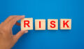 Risk management concept. Wooden cubes with the word risk isolated on a blue background. Top view. Close-up photo.