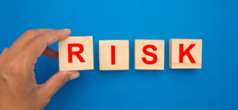 Risk management concept. Wooden cubes with the word risk isolated on a blue background. Top view. Close-up photo.