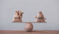 Risk and reward bags on a basic balance scale in equal position on wood table. risk management concept, depicts investors use a risk-reward ratio to compare the expected return of an investment