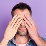 Photo of young man serious close cover eyes hands prosthesis rehabilitation disability isolated over purple color background