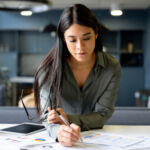 Latin American business woman working on a financial report at a coworking office