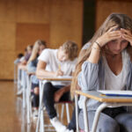 Anxious Teenage Student Sitting Examination In School Hall