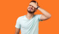 Facepalm. Portrait of desperate brunette man with beard in white t-shirt covering face with hand, feeling sorry and blaming himself for the mistake. indoor studio shot isolated on orange background
