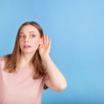 Beautiful woman does not hear on blue background