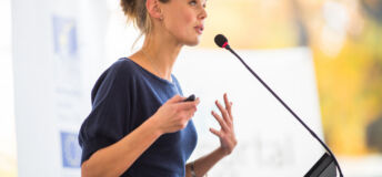 Pretty, young business woman giving a presentation in a conference/meeting setting (shallow DOF; color toned image)