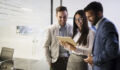 Team of young colleagues working together on tablet in office