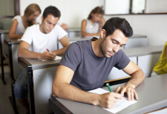 Good-looking male student writing an exam