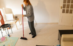 RCW exclusive: A sweep exam letter for Reg S-P Woman performing household chores, sweeping tiled floor with a red broom in her home