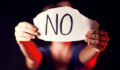 Woman holds paper with message to help her in front of black background.