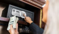 Woman opening the safe to put the money in it.