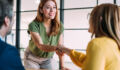 Businesspeople handshaking across the table during a meeting in modern office. Group of business persons in business meeting. Shot of three entrepreneurs on meeting in board room. Creative business team on meeting in the office.